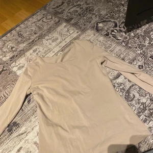 Beige långärmad topp - Säljer en stilren beige långärmad topp i mjukt material. Perfekt för en enkel och avslappnad look. Passar bra till både jeans och kjol.