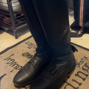 Svarta ridstövlar med snörning - Ridstövel Clifton CRW Snygga svarta ridstövlar i skinn med snörning och dragkedja baktill. Perfekta för ridning med en klassisk design och robust konstruktion. Endast använda två gånger då var dom ej helt dragna då dom inte passade mig i vaderna. Ny pris 1299