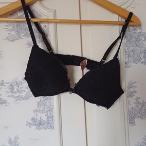 Svart spets-BH från Hunkemöller - Säljer en elegant svart BH från Hunkemöller med spetsdetaljer. Den har justerbara axelband och en klassisk knäppning bak. Perfekt för att känna sig både bekväm och stilfull.