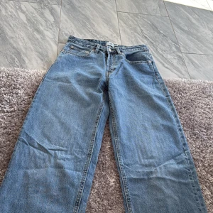 Blå jeansbyxor - Säljer ett par klassiska blå jeansbyxor med fem fickor och knappgylf. De har en rak passform och är perfekta för en avslappnad stil. Passar bra till både sneakers och kängor.