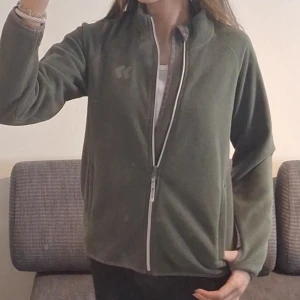 Grön fleecejacka med dragkedja - Säljer en grön fleecejacka med dragkedja framtill. Är I storlek 150 men ha XS å kan ha den💕