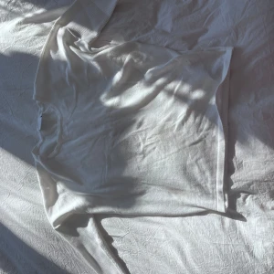 Vit långärmad tröja - Säljer en stilren vit långärmad tröja med ribbade muddar vid ärmsluten. Perfekt för en enkel och klassisk look. 