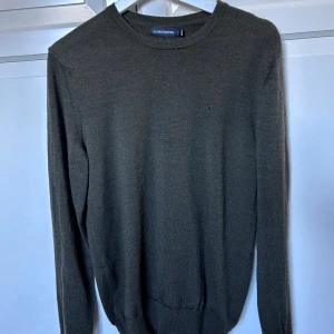 Grön tröja från J.Lindeberg. - Snygg mörkgrön 100% merino ull  tröja från J.Lindeberg i en klassisk design. Tröjan har långa ärmar och en rund halsringning. Perfekt för en stilren look. Hör av er vid intresse/ frågor!