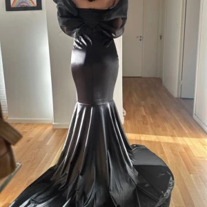 Balklänning - Elegant svart axelbandslös långklänning med en dramatisk volangdetalj över axlarna från & Other Stories