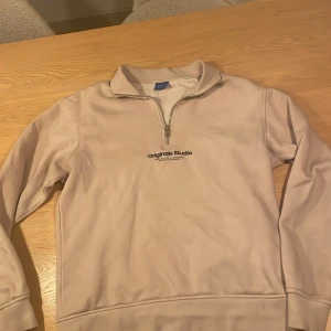 Beige tröja från Jack & Jones - Säljer en beige tröja från Jack & Jones Originals Studio med dragkedja vid halsen. Använd men i gott skick, storleken är xs men passar S också