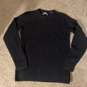 Svart stickad tröja från Jack & Jones - Säljer en stilren marinblå stickad tröja från Jack & Jones. Tröjan har en klassisk rund hals och långa ärmar med ribbade muddar. Storlek 164, men är stor i storlek så passar även 170-xs