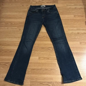 Blå bootcut low waisted jeans från Zara - Låg midjade snygga blåa bootcut jeans från Zara med klassisk femficksdesign och knappgylf. Perfekta för en avslappnad stil med en touch av retro. De har en bekväm passform och är tillverkade i slitstarkt denim. Har använts 2 -3 gånger.