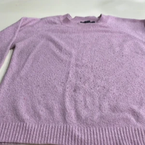 Ljuslila tröja från Vero Moda - Säljer en stilren ljuslila tröja från Vero Moda. Tröjan har en klassisk design med rund hals och ribbade kanter vid ärmslut och nederkant. Perfekt för en avslappnad och trendig look.