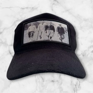 Svart keps med vintagebild - Snygg svart keps med en cool vintagebild framtill. Kepsen har ett nätmaterial baktill för bra ventilation och justerbar passform. Perfekt för en avslappnad stil.