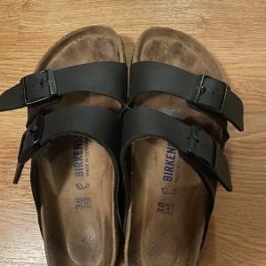 Svarta sandaler från Birkenstock - Säljer ett par klassiska svarta sandaler från Birkenstock med dubbla remmar och justerbara spännen. Sandalerna har en slitstark sula💓