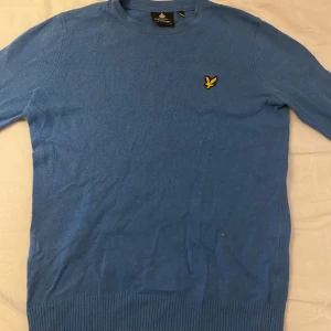 Blå tröja från Lyle & Scott - Säljer en snygg blå tröja från Lyle & Scott med deras ikoniska logga på bröstet. Tröjan har en rund hals och långa ärmar, perfekt för en stilren look. Passar bra till både jeans och chinos.