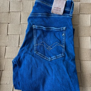 Blå jeans från Replay Hyperflex - Snygga blå jeans från Replay Hyperflex med klassisk femficksdesign och broderad bakficka. Perfekta för en avslappnad stil med en modern touch. Passform slim.