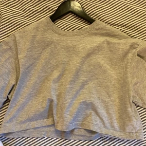 Grå croppad t-shirt från Gina Tricot💓 - Säljer en stilren grå croppad t-shirt från Gina Tricot, perfekt för en avslappnad look. T-shirten har en rund halsringning och korta ärmar. Enkel och bekväm att bära till vardags❤️