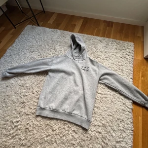 Grå hoodie  - Säljer en grå hoodie med texten 'JE M'EN AMOUR' tryckt på både fram- och baksidan. Tröjan har en klassisk design med huva och långa ärmar. Perfekt för en avslappnad stil. Storlek 146/152. Pris kan diskuteras💕