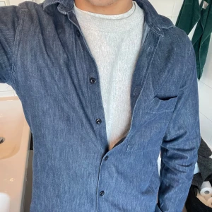 Blå overshirt från NN07 - Snygg blå overshirt från NN07 i ett stilrent och enkelt utförande. Skjortan har långa ärmar och knappar framtill. Perfekt för lager-på-lager-stil och passar bra till både t-shirt och tröja under.