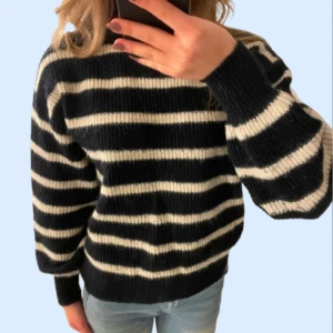 Stickad tröja - Säljer en svart/marinblå och vit randig stickad tröja. Den är väldigt bekväm och i bra skick. Tröjan har ribbade muddar vid ärmslut och nederkant. 