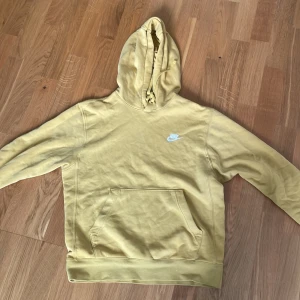 Gul hoodie från Nike - Säljer en snygg gul hoodie från Nike med klassisk logga på bröstet. Tröjan har en stor ficka framtill och en bekväm huva med snören. Storlek XS men passar även S. Skriv vid frågor!