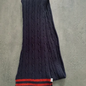 Boomerang Stickad Lamm Ull Halsduk - En lyxig och mjuk stickad halsduk från Boomerang, tillverkad i en ull/nylon-blandning för både värme och hållbarhet. Perfekt för kyliga dagar, denna halsduk kombinerar stil och funktion med sin eleganta design och högkvalitativa material. Ursprungligt pris: 900 kr.