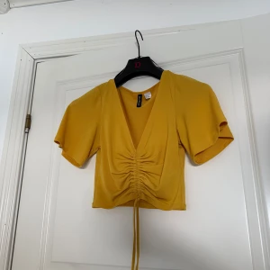 Gul kortärmad topp med knyt - Snygg gul topp med korta ärmar och knytning framtill.