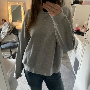 Grå sweatshirt - Säljer en grå sweatshirt med rund hals och långa ärmar. Tröjan har ribbade muddar vid ärmslut och nederkant. Står ingen storlek i men skulle uppskatta den som ungefär en storlek S, kanske lite större.