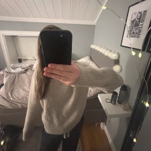 Beige stickad tröja från H&M - Säljer en mysig beige stickad tröja från H&M. Tröjan har en ribbad design och långa ärmar, perfekt för kyligare dagar. Den är enkel att matcha med olika outfits och ger en stilren look.