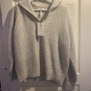 Säljer en mysig grå stickad tröja från Object. Tröjan har en dragkedja vid halsen och långa ärmar. Den är i storlek XL, aldrig använd ny med prislappen på