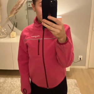 Rosa fleecejacka från Everest - Säljer en rosa fleecejacka från Everest med dragkedja och hög krage. Jackan har en bröstficka med dragkedja och är perfekt för kyliga dagar. Den är bekväm och stilren med en sportig look.