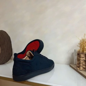 Loubs  - Snygga svarta sneakers från Christian Louboutin med den ikoniska röda sulan. Skorna har en stilren design med snörning och är perfekta för den som vill ha en touch av lyx i vardagen.