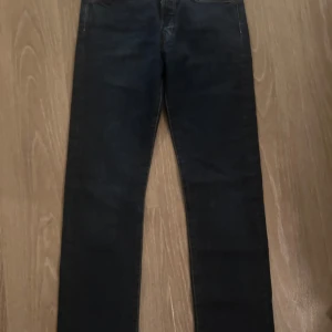 Levi's 501 jeans i mörkblå denim - Klassiska Levi's 501 jeans i mörkblå denim. De har en rak passform och är tillverkade i slitstarkt jeansmaterial. Perfekta för en tidlös stil. Märkeslappen syns tydligt på baksidan.
