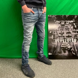 Jeans med slitningar - Snygga blå jeansbyxor med en slim passform och coola slitningar. De har en klassisk femficksdesign och en läderpatch på baksidan av midjan. Perfekta för en avslappnad stil.