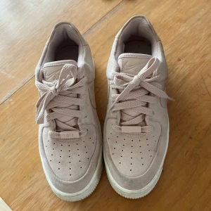 Beige/rosa Nike Air Force sneakers - Snygga beige Nike Air Force sneakers i mocka med klassisk design och snörning. Skorna är i storlek 37