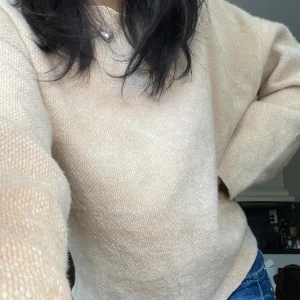Beige stickad tröja - Mysig beige stickad tröja med långa ärmar. Perfekt för kyligare väder och enkel att matcha med olika outfits. Mjukt material.