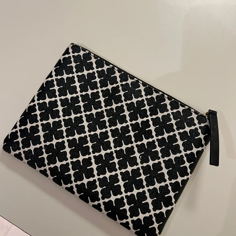 Snygg kuvertväska från Malene Birger i svartvitt mönster. Väskan har en praktisk dragkedja och ett stilrent mönster som ger en elegant touch. Perfekt för att bära med sig det nödvändigaste.. Laukut & Käsilaukut.