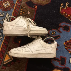 Vita Nike Air Force sneakers - Säljer ett par klassiska vita Nike Air Force sneakers. De har en stilren design med snörning och perforerade detaljer på ovansidan för ventilation. Perfekta för en casual look.