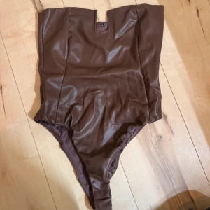 Brun baddräkt - Snygg brun body i ett glansigt material med en unik fyrkantig urringning. Perfekt för en stilren look, från Zara men går inte att få tag på längre. I väldigt bra skick 