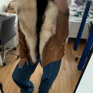 Brun mockajacka med fuskpäls - Säljer en snygg brun mockajacka från Zara med avtagbar fuskpäls på kragen. Jackan har dragkedjor och knappar för en cool look. Perfekt för höst och vinter. 🧥✨