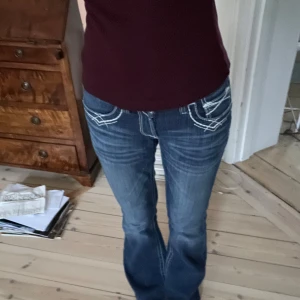 Lågmidjade bootcut jeans - Snygga blå jeans med vita broderade detaljer på bakfickorna. Midjemått är 37cm rakt över, skriv vid frågor💗