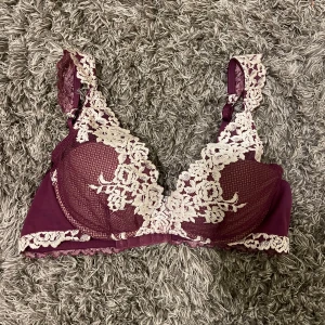  Intimissimi bh med spetsdetaljer - Säljer en elegant vinröd bh med vackra vita spetsdetaljer. Bh:n har justerbara axelband och en klassisk knäppning bak. Perfekt för att känna sig både bekväm och stilfull.