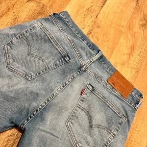 Blå jeans från Levi's - Snygga blå jeans från Levi's med klassisk femficksdesign och en bekväm passform. De har en ljus tvätt och är perfekta för en avslappnad stil. Märkeslappen i läder sitter på baksidan av midjan.