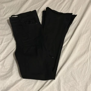 Svarta jeans från Perfect Jeans - Snygga svarta jeans från Perfect Jeans i storlek M. De har en klassisk design med en slits nere vid slutet på byxan och är tillverkade i ett bekvämt material. Perfekta för en stilren look.