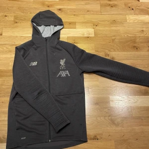 New balance Liverpool Zip hoodie - Detta är en grå New balance zip, som är sjukt nice, säljer den för att jag inte har någon användning för den längre, den passar folk som har M i vanlig storlek. 