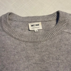 Grå kashmirtröja från Soft Goat - Säljer en supermjuk och stilren grå kashmirtröja från Soft Goat. Tröjan har en klassisk rund halsringning och långa ärmar, perfekt för kyliga dagar. Den är tillverkad i 100% kashmir vilket gör den extra lyxig och bekväm. Perfekt för att hålla dig varm och snygg! 🐐