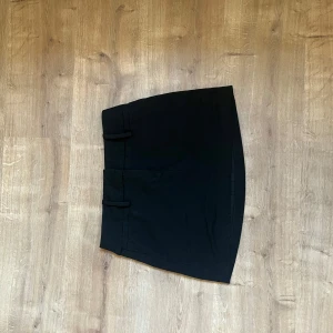 Svart kortkjol - Snygg svart kortkjol med en stilren design. Perfekt för att matcha med olika toppar och accessoarer. Kjolen har en enkel och elegant look som passar till många tillfällen.