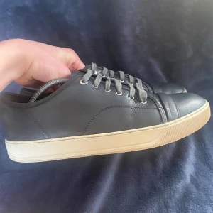 Svarta sneakers från Lanvin - Snygga svarta sneakers från Lanvin i skinn med grå snörning. Perfekt för en adel outfit. SKICK 6/10✅ För det är in defekt på sulan Bild 4. Sulan går att tvätta med rätt redskap som sulkräm och sultvätt. Allt på bild 5 följer med ✅Skriv om ni vill ha mer bilder eller har några funderingar❤️ priset är inte hugget i sten.
