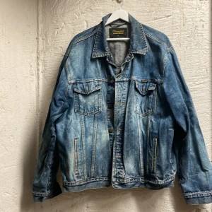 Blå jeansjacka från Wrangler - Säljer en oversized blå jeansjacka från Wrangler. Jackan har långa ärmar, knappar framtill och två bröstfickor med lock. 