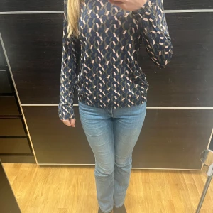 Mönstrad långärmad topp - Säljer en snygg långärmad topp med ett geometriskt mönster i blått, brunt och rosa. 