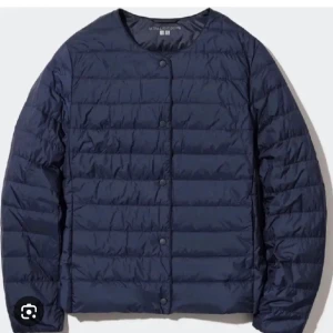 Mörkblå dunjacka från Uniqlo - Säljer en stilren mörkblå dunjacka från Uniqlo. Jackan har en quiltad design med knappar framtill och långa ärmar. Perfekt för kyligare dagar och lätt att bära med sig. Den har tyvärr blivit repad på ryggen som man ser på sista bilderna!