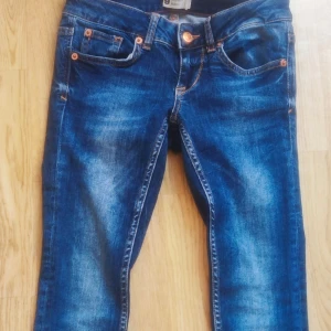 Blå jeans från Perfect Jeans - Snygga blå jeans med en klassisk femficksdesign och orangea sömmar. De har en normal passform och är perfekta för en avslappnad stil. Märkeslappen syns tydligt på baksidan.
