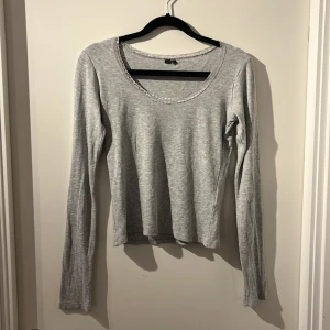 Grå långärmad topp - Säljer en stilren grå långärmad topp med rund halsringning. Perfekt för en avslappnad look. Toppen är i ett mjukt material som känns skönt mot huden.