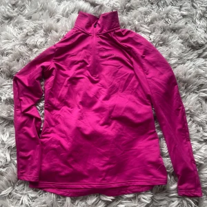 Rosa långärmad tröja med dragkedja - Säljer en snygg rosa långärmad tröja med halv dragkedja framtill. Perfekt för kyligare dagar och passar bra till både träning och vardag. Tröjan har en hög krage för extra värme.
